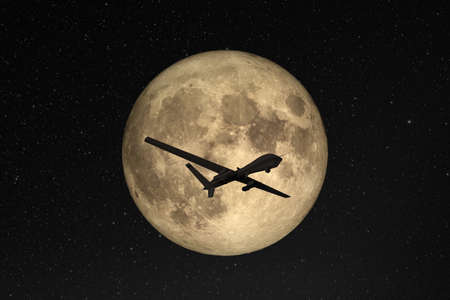 Silhouette of unmanned aerial vehicle (UAV) flying against background of huge full moon in dark...