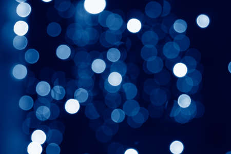 abstract blurred circular bokeh lights background toned in trendy Classic Blue color of the Year...
