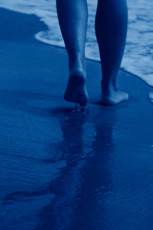woman walking on sand beach leaving footprints in the sandの写真素材