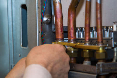 worker installs the heat exchanger after descaling on a workplace in the gas boilerの写真素材