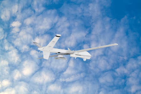 military RC military drone flies against the backdrop of blue peaceful sky with white clouds
