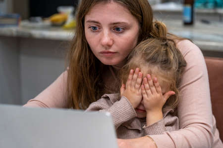 Mother working from home with baby toddler. Busy young single parent caucasian mother using laptop...