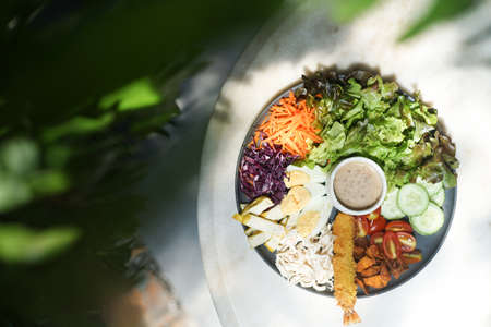 Fresh vegetable salad, healthy food, non-toxic tomatoes, cucumbers, lettuce, carrots, purple cauliflower, boiled egg, chicken, fried potatoes, fresh shrimp, special salad dressingの写真素材