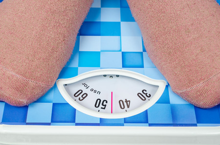 weight woman standing on a retro style weighing machineの写真素材