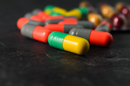 Drug prescription for treatment medication. Pharmaceutical medicament, cure in container for health. Pharmacy theme, Heap of red orange white round capsule pills with medicine antibiotic in packages.の写真素材