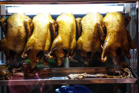 a whole roasted duck in cranberry marinade directly on a cutting board with silverware on the sideの写真素材