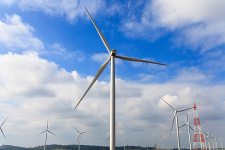 Wind turbines generate electricity in the mountains and the blue and white sky.の写真素材