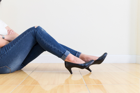 Woman blue jeans Wearing High-heeled shoes ,sitting cross-legged On a white backgroundの写真素材