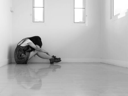 Woman sitting strain ,unhappy In the corner on the bow the knee In the corner of the room, even when the light shines.の写真素材