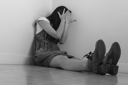 Woman sitting strain ,unhappy In the corner on the bow the knee In the corner of the room, even when the light shines,White and blackの写真素材