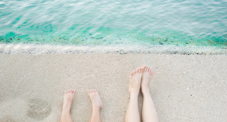 Children and adults leg stretch on the beach,Clear water seaの写真素材