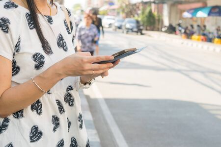 Women play mobile smartphone on a roadside.の写真素材
