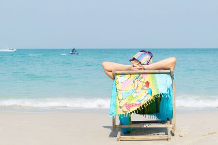 Woman sitting on the seat, sunbathing on the beach in Chonburi, Thailand.の写真素材
