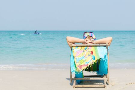 Woman sitting on the seat, sunbathing on the beach in Chonburi, Thailand.の写真素材