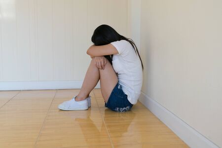 Woman sitting strain ,unhappy In the corner In the corner of the room, even when the light shines,blurの写真素材