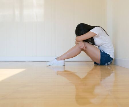 Woman sitting strain ,unhappy In the corner In the corner of the room, even when the light shines,blurの写真素材
