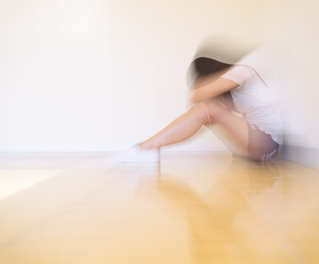 Woman sitting strain ,unhappy In the corner In the corner of the room, even when the light shines,blurの写真素材