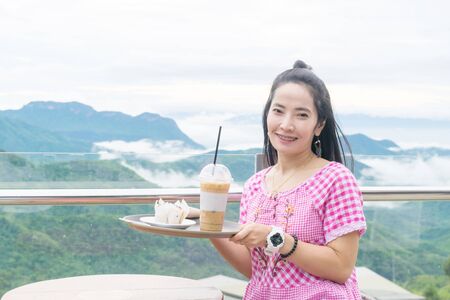 Woman holding a cup of iced coffee mountain backgroundの写真素材