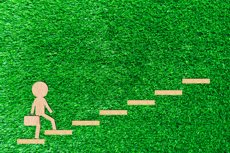 Walking man carry a bag up the stairs walks up to the goal to succeed paper cut of a green backgroundの写真素材