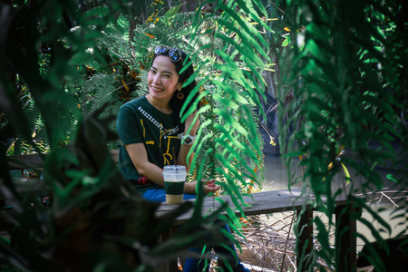 Lady fefreshing drink iced coffee on the table in the forest greenの写真素材
