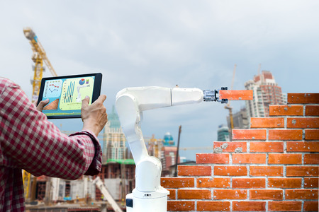 Man holding a tablet Remote control Smart robot industry 4.0 arm brick building construction human force remote wifiの写真素材