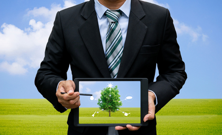 Men holding touch screen tablet technology environment and ecology of trees.の写真素材