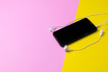 Smartphones and headphones Listen to vintage music on a yellow and pink background.の写真素材