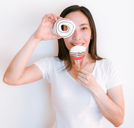 Women asia wearing white shirts holding donuts to eatの写真素材