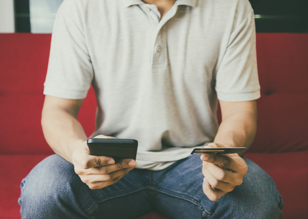 Man's hands holding shopping and credit card manage online payment by using smart phone vintage imageの写真素材