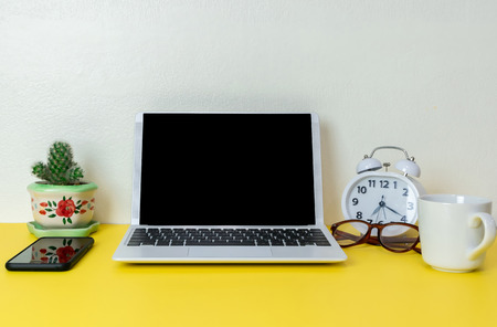 Laptop placed on a yellow table background of business working place with cup coffee, Empty workspaceの写真素材