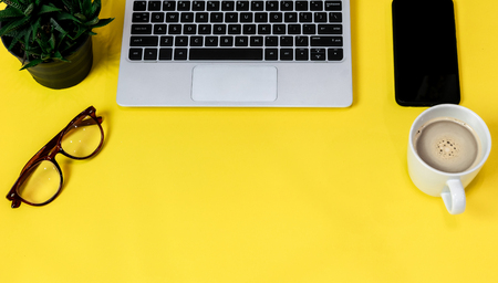 Laptop placed on a yellow table background of business working place with cup coffee, Empty workspaceの写真素材