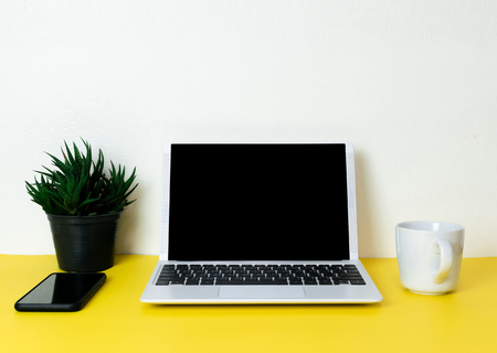 Laptop placed on a yellow table background of business working place with cup coffee, Empty workspaceの写真素材