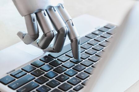 Robot hands and fingers point to laptop button advisor chatbot robotic artificial intelligence conceptの写真素材