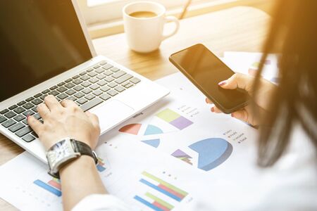 Women analyze graphs and charts financial profits from businessの写真素材