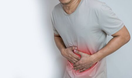 Man suffering from stomach ache with both palm around waistline to show pain and injury on belly areaの写真素材