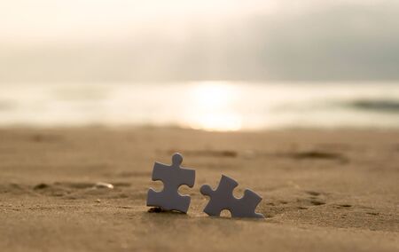 Jigsaw on the beach sand matching puzzle pieces togetherの写真素材