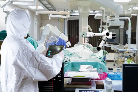 The doctor controls the medical robot to treat patients.の写真素材