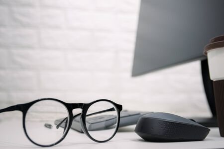 Working desk with glasses placed and computer monitorsの写真素材