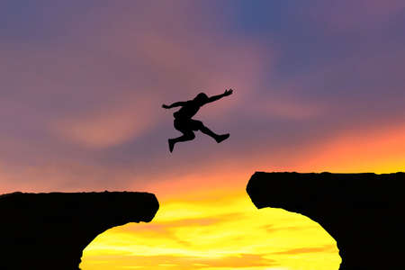 Men jump cliff sun light over silhouette conceptの写真素材