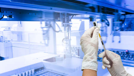 holds a syringe with a liquid vaccine in development laboratory