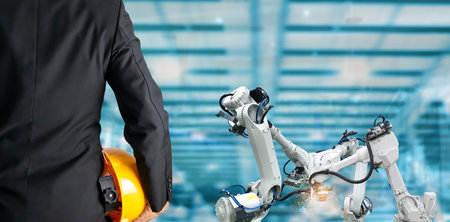 Engineer holding helmet. Industrial robotics concept in factory.の写真素材