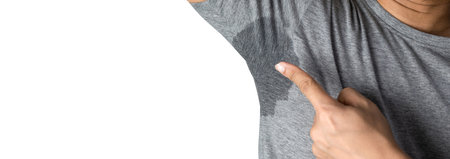 Sweaty man with stain wet armpit on t-shirt against gray free spaceの写真素材