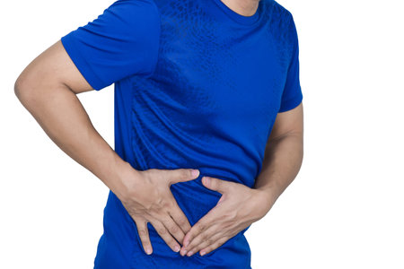 A man has a stomachache and holds his stomach with his hand.の写真素材