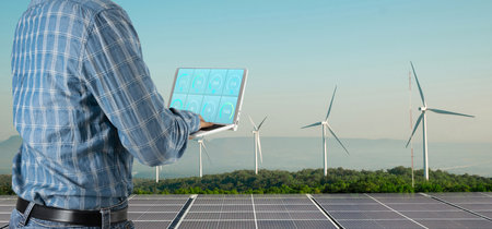 Engineers inspect clean energy systems solar cells and wind turbines.の写真素材