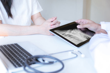The doctor examines the patient and looks at an X-ray of the shoulder.の写真素材