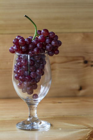 Red grapes in a glass on a wooden background.の写真素材