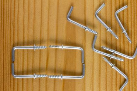 L Shaped Self Tapping Metal Screw Hook on wooden background. Top view.