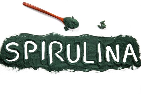 Organic spirulina algae powder in a wooden spoon and spirulina capsules on white background, Spirulina is a superfood used as a food supplement source and detox healthy nutrition-concept, top viewの写真素材