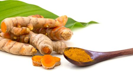 Turmeric (curcumin) powder in wooden spoon and raw organic  turmeric roots with green leaves on white background, Used for food and healthy seasoning ingredient, Indian spice and medicinal herbの写真素材