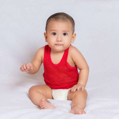 Happy baby wearing red t-shirt.Cute kids in a good mood Sit down on the couchの写真素材